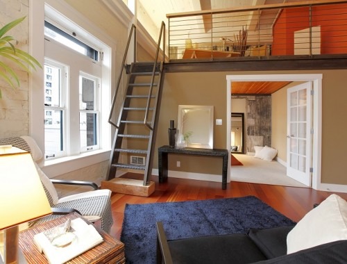 View of modern reconstructed living room with mezzanine area above bedroom. View of iron steep stairs